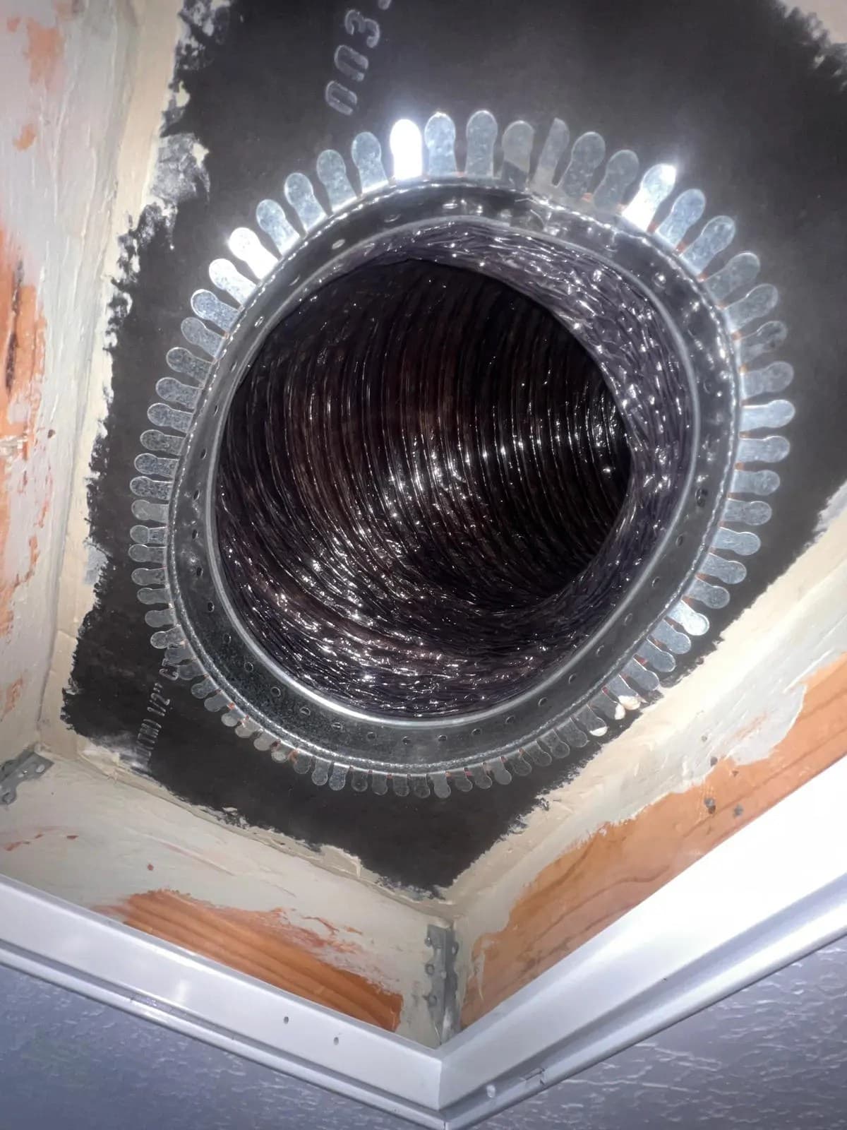 Professional duct-cleaning equipment with a rotary brush inside an opened floor register