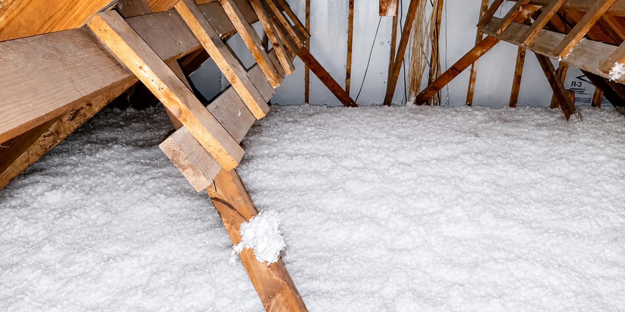 Worker installing blown-in fiberglass insulation in a Houston attic