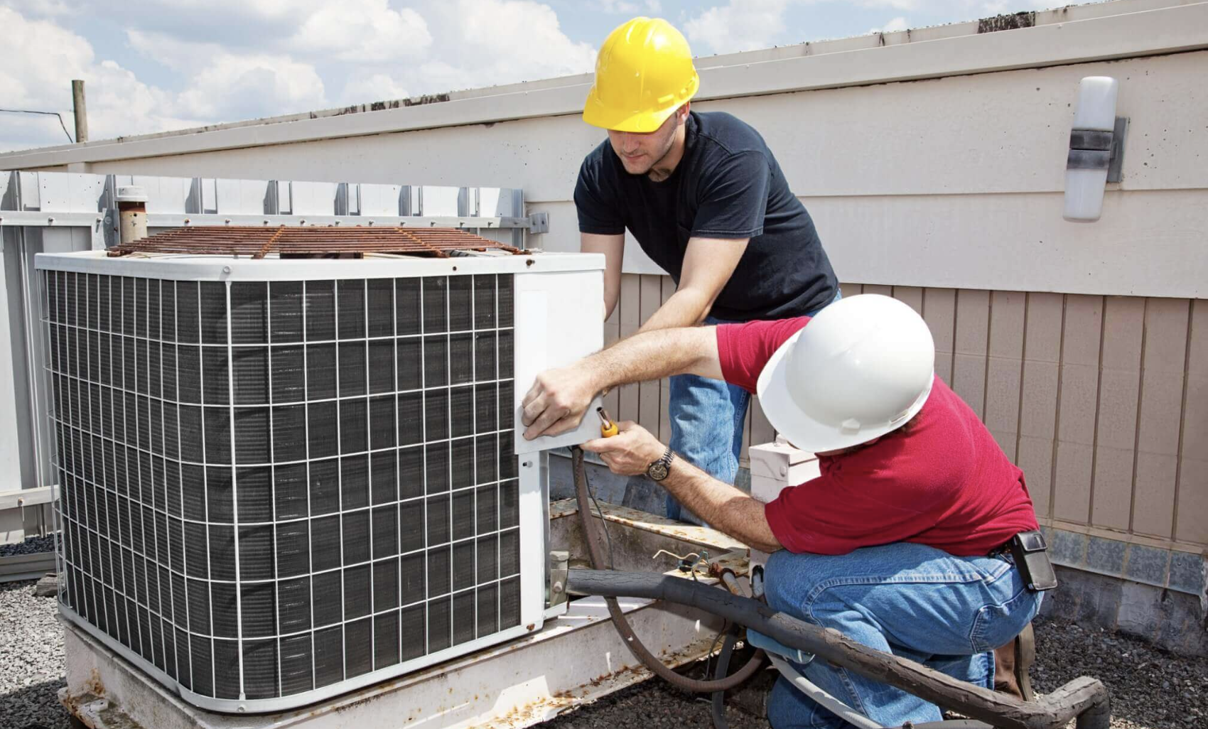 two workers performing maintenance on a HVAC system