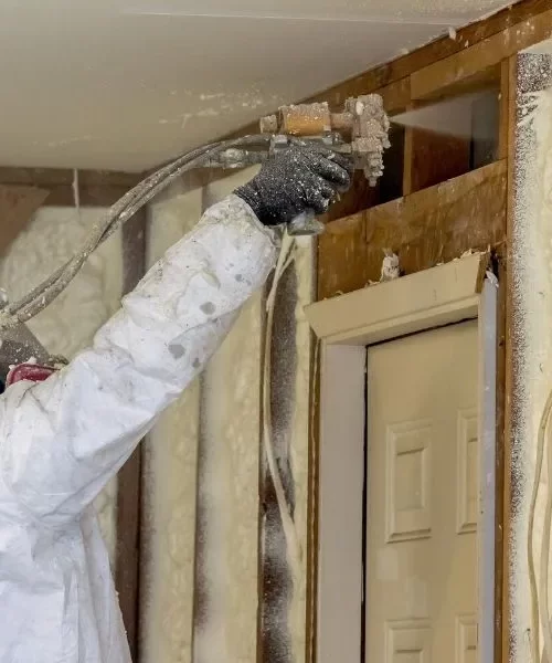 spray foam insulation installed with hose by a worker wearing protection gear